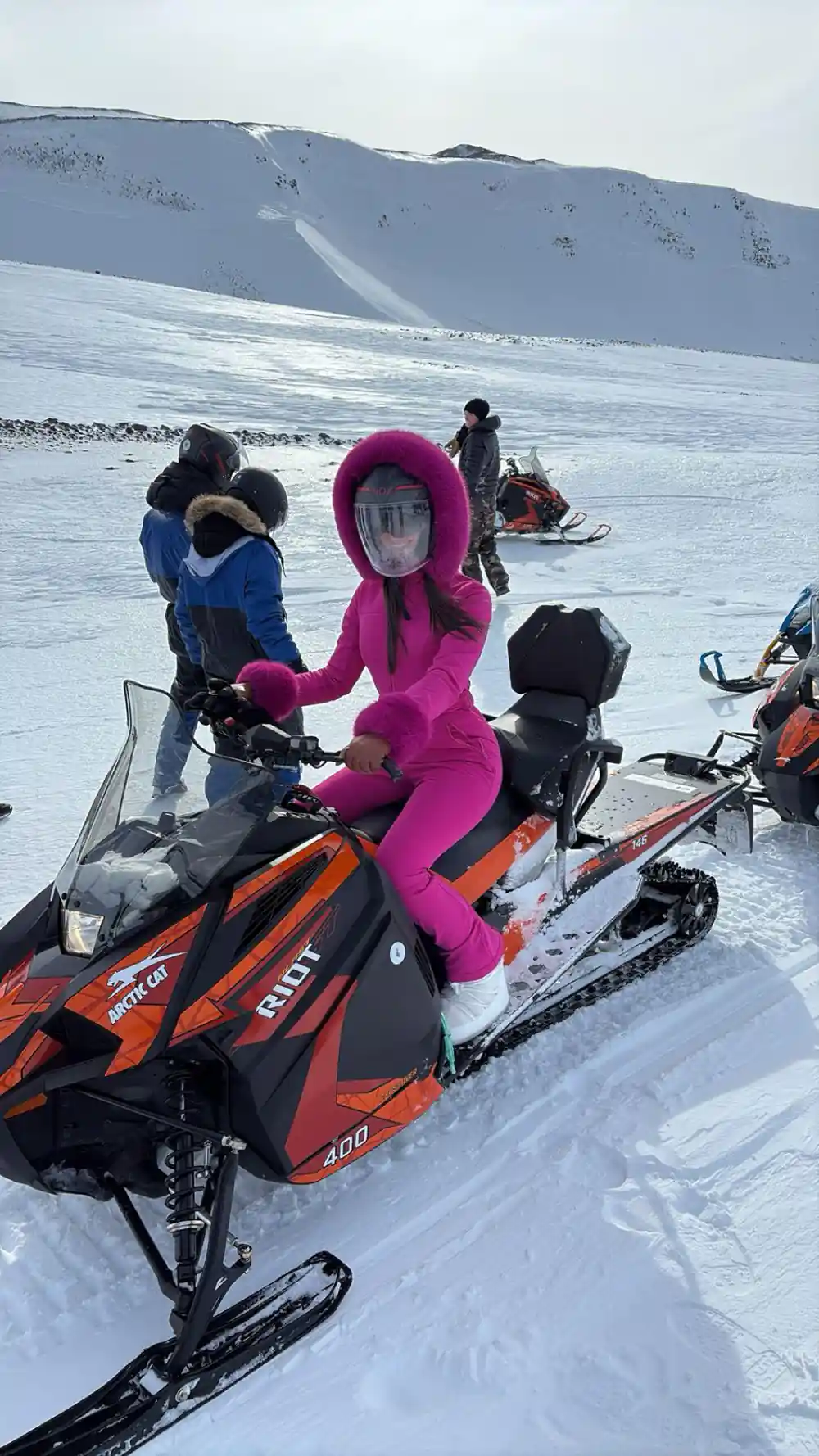 Child on orange snowmobile with mountains in background