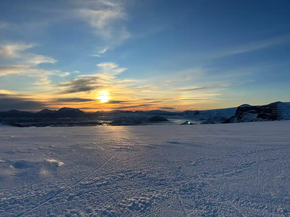 Frozen lake landscape at sunset with mountains