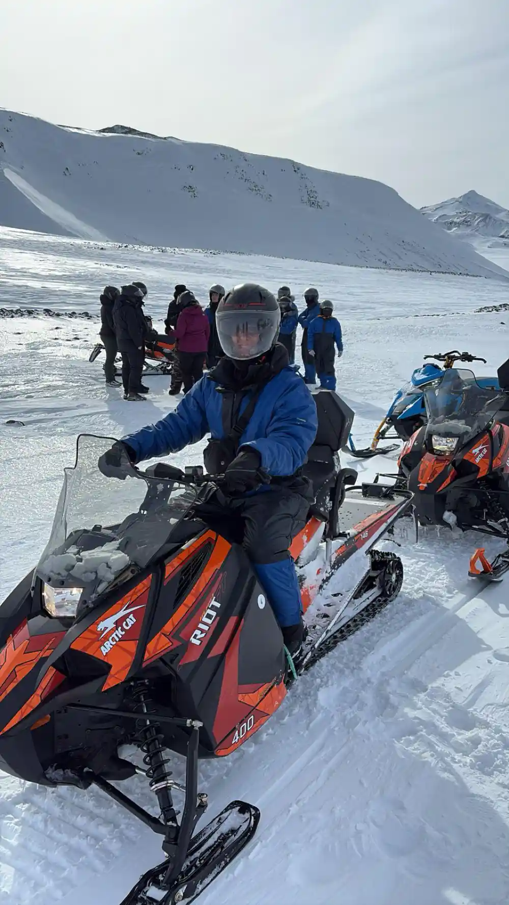 Group of people with snowmobiles and mountains
