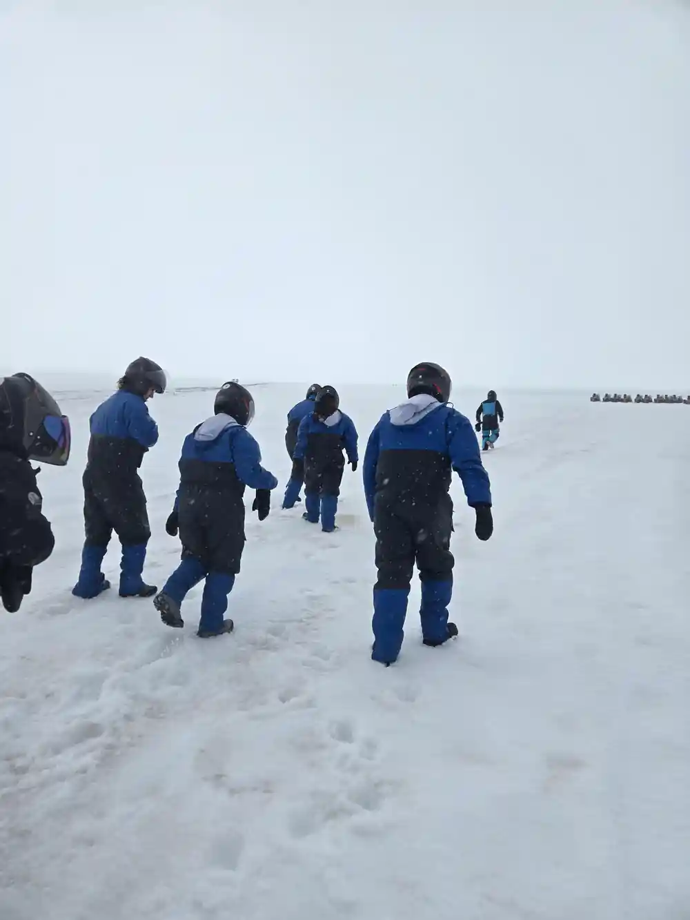 Group of people walking across frozen glacier surface