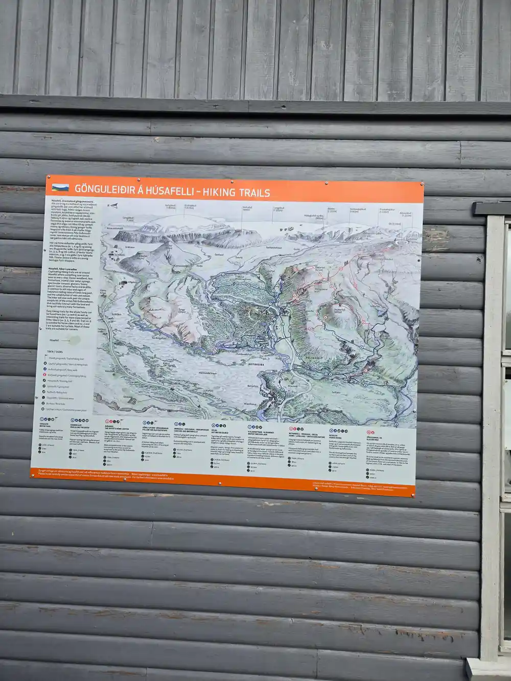 Hiking map posted on wooden building exterior wall
