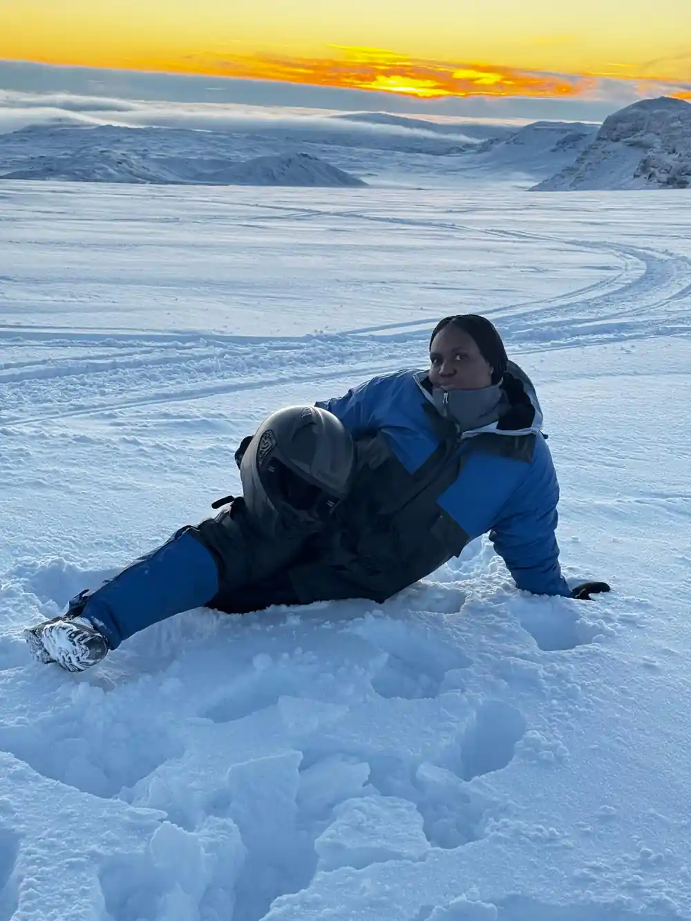 Person lying on frozen lake at golden hour