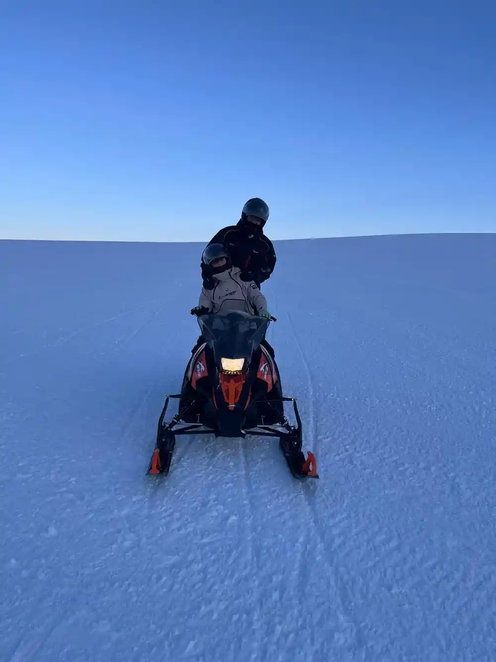 Person riding snowmobile across completely flat frozen landscape