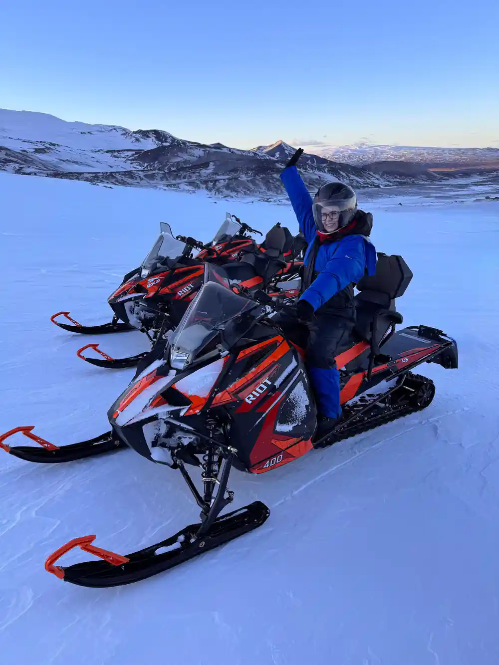 Person sitting on snowmobile in snowy landscape