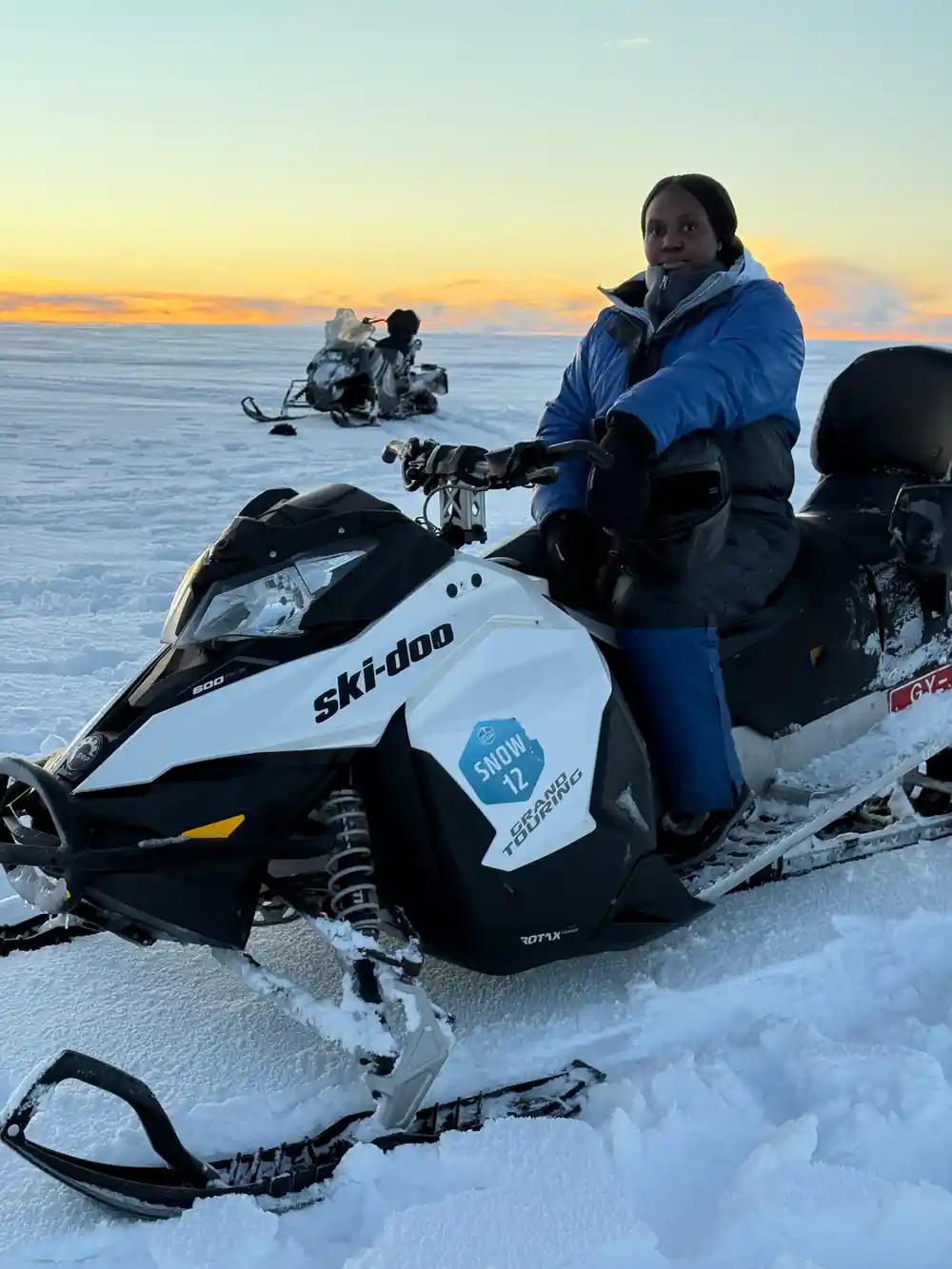 Person on snowmobile at sunset with mountains