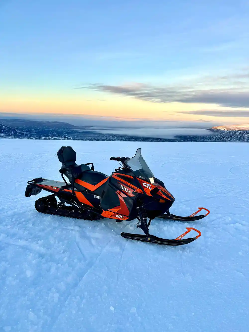Single snowmobiler on frozen lake with distant mountains
