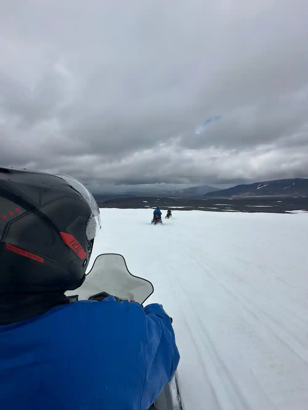 Snowmobile on frozen lake with mountains and cloudy sky