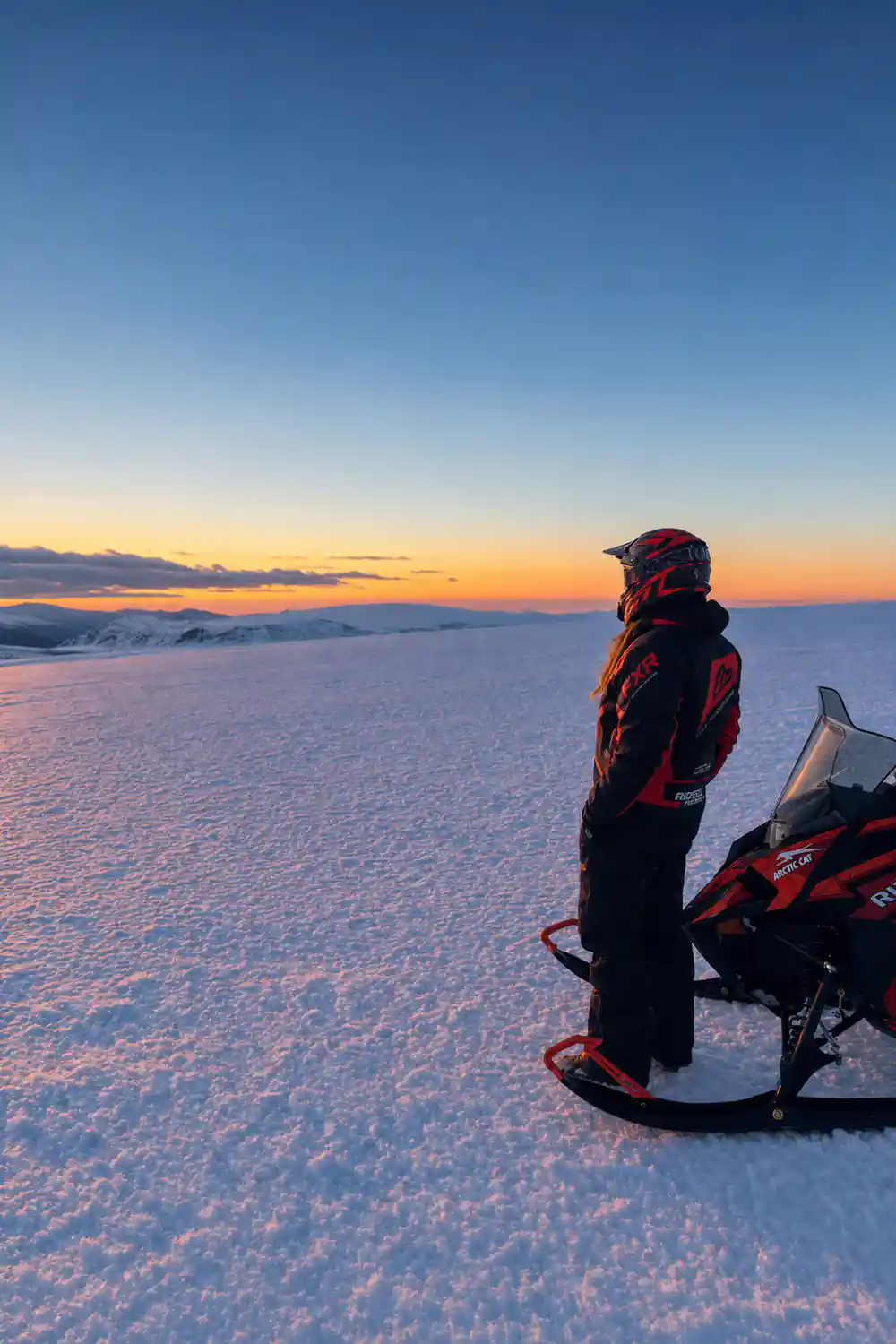 Snowmobile parked on frozen lake at dusk