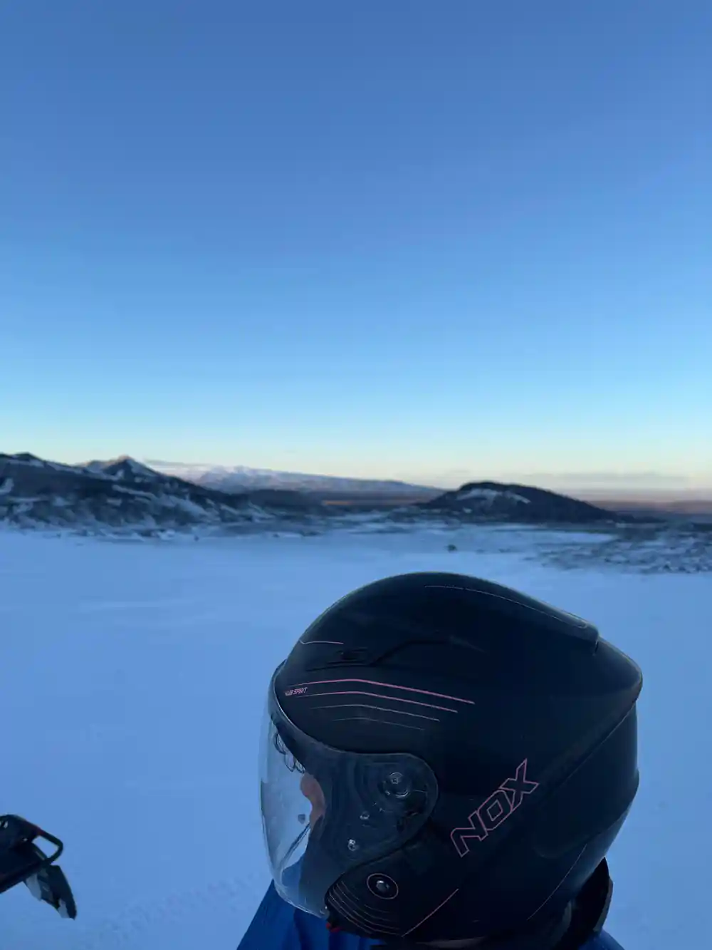 Snowmobile windscreen with helmet visor and snowy landscape