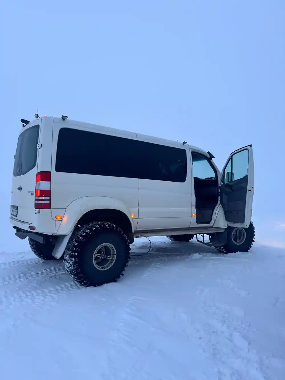 White van with door open on frozen snowy landscape